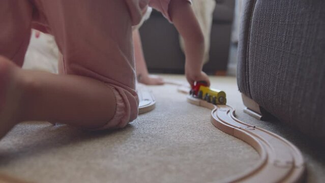 Close up of Mother and daughter at home playing with wooden train set toy on carpet - shot in slow motion