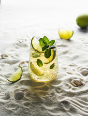 Summer healthy lemonade, cocktails of citrus infused water or mojitos, with lime, ice and mint, diet detox beverages, in glasses on a summer beach.