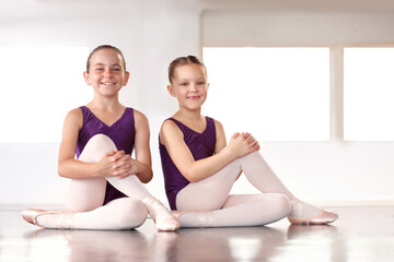 Ballerinas in the making. Happy young ballerinas sitting in a ballet studio.