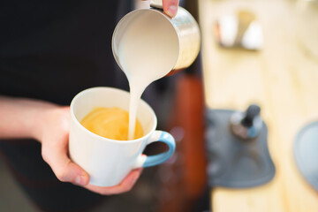 Obraz na płótnie Canvas barista pouring milk into espresso coffee for making cappuccino, latte art