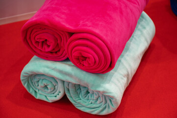Rolled clothes fabrics samples lie on red table in hall