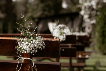 Fototapeta na wymiar white gipsophyla bouquets on rustic wedding chairs at wedding place. Wedding day.