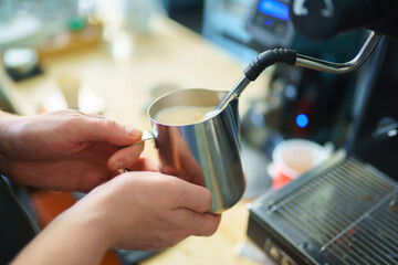 barista frothing milk for cappuccino, close up