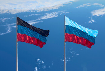 Flags of the Donetsk and Lugansk People's Republics against a cloudy sky.