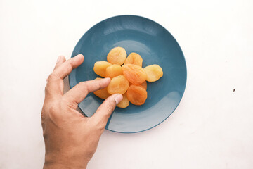hand pick apricot fruit half on plate on white background 