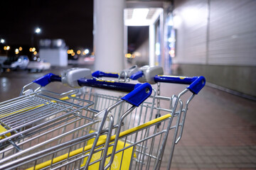 Selective focus on a shopping cart near a supermarket at night. An empty shopping cart in a store...