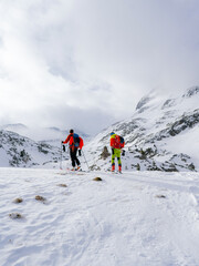 Ski touring couple hiking up a summit in the alps. Concepts: adventure, achievement, courage, determination, extreme sport