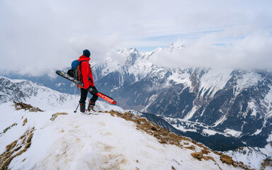 Mountaineer with skiers climbing up a rock in the mountains in winter