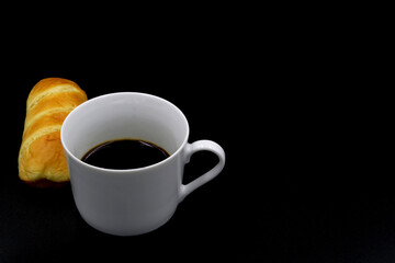 Butter bread next to a cup of coffee with a black background