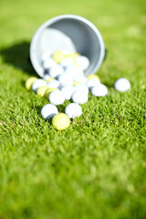 Picking the correct golf ball is important. Shot of a bucket of golf balls on a golf course. © Thomas T/peopleimages.com