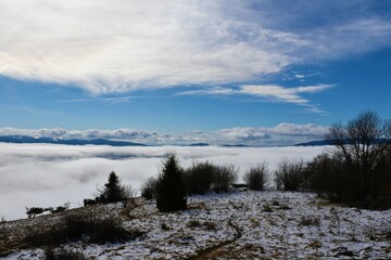 View from the top of mountain Slivnica in Notranjska, Slovenia with Javorniki mountains rising above the clouds
