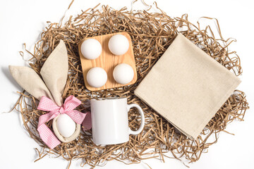 Easter mockup mug and linen napkin with bunny ears and easter eggs on white background. Flat lay,...