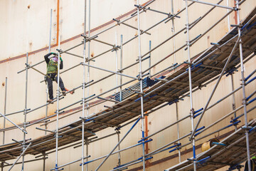 Worker male assembly in progress storage tank oil inspection scaffolding work at high