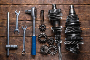 Disassembled parts of car gearbox and work tools wrenches on the wooden flat lay workbench...