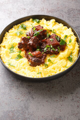 Typical dish of Brazilian cuisine Rabada Oxtail with corn porridge closeup on plate on the concrete table. Vertical