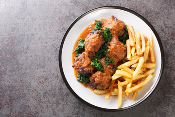 Tasty Rabo de toro or oxtail stew served with french fries on white plate on the concrete table. Horizontal top view from above