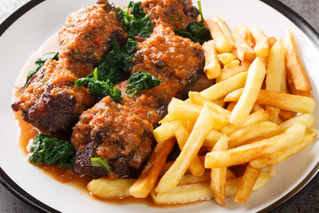 Meat for bull tail stew Rabo de toro served with french fries on white plate on the concrete table. Horizontal