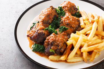 Tasty Rabo de toro or oxtail stew served with french fries on white plate on the concrete table. Horizontal
