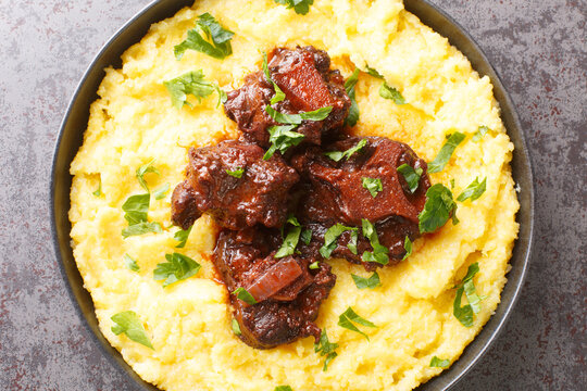 Oxtail rabada traditional dish of Brazilian cuisine closeup on plate on the concrete table. Horizontal top view from above