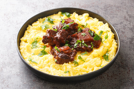 Oxtail rabada traditional dish of Brazilian cuisine closeup on plate on the concrete table. Horizontal