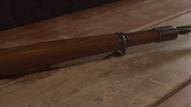 Dolly out from old WW2 era rifle, revealing live ammunition lying on wooden surface