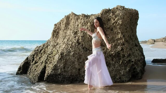 Beautyful belly dance performing belly dance barefoot on the beach. Oriental.
