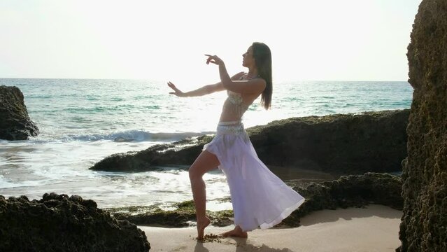 Beautyful belly dance performing belly dance barefoot on the beach. Oriental.