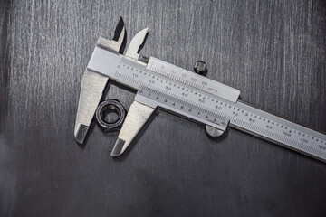Vernier Caliper measures the screw nut size for precise details. pasted on a steel metal plate with a gray, black surface