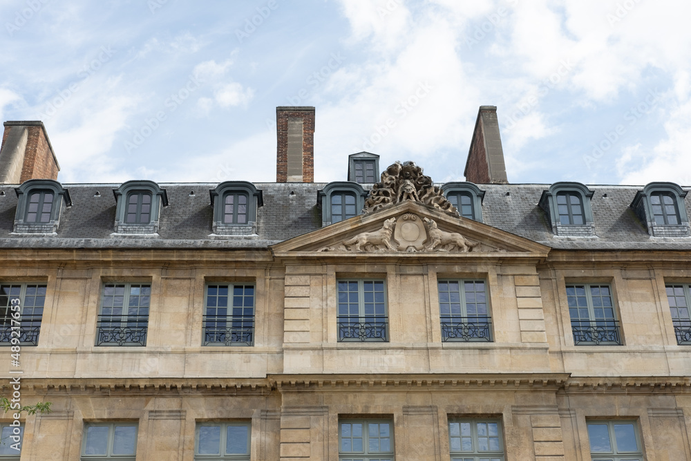 Poster low angle view of an old building with ornated facade with windows reflecting the cloudy sky