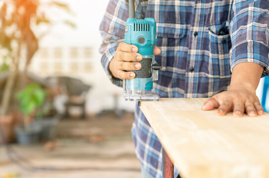 The carpenter using a trimmer to cut edging plank.