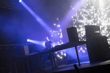Dj playing techno music on the concert stage at summer night	