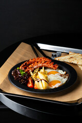 Breakfast eggs with sausage and salad close up food on dark table