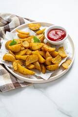 Crispy baked potatoes and ketchup on plate