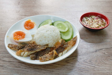 slice deep fried salty mango or Tilapia fish with rice topping boiled egg on plate dipping spicy sauce