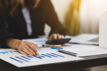 Businessman or accountant hand working on calculator to calculate business data, accounting document and laptop computer at office, business concept.