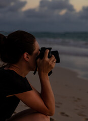 Young woman photographer taking a picture with her lens camera. Woman looking through her photo...