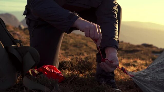 A person putting up a tent and using boot on peg