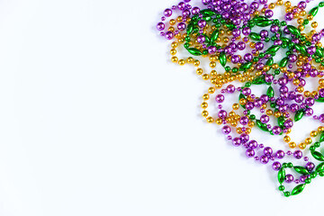 Mardi Gras background. Gold, green and purple beads on white background. Fat Tuesday symbol.