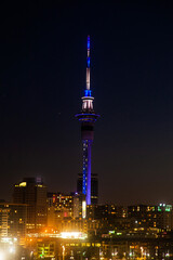 Sky Tower at night in Auckland, New Zealand by the light of nightly skyscrapers.
