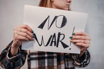 Young woman holding a placard protesting No to war