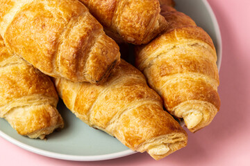 Fresh croissants on a pink background. Tasty breakfast. Traditional pastries.