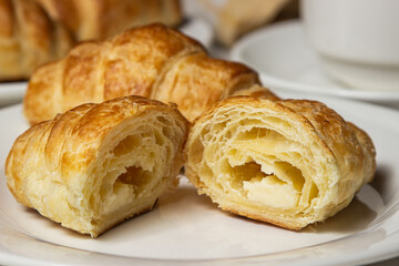 Croissant cut in half on a white plate. Tasty breakfast. Traditional pastries.