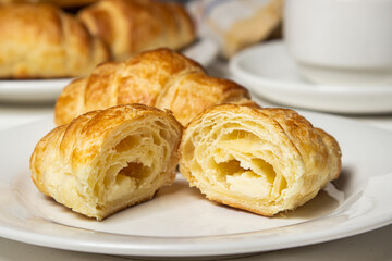 Croissant cut in half on a white plate. Tasty breakfast. Traditional pastries.