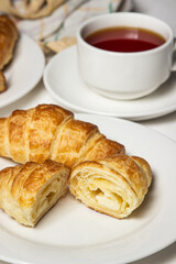 Croissant cut in half on a white plate. Tasty breakfast. Traditional pastries.