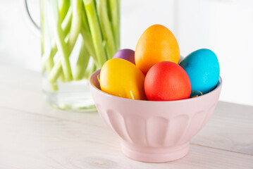 Easter colored eggs in a plate on a wooden table.