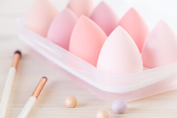 Cosmetic sponges in the form of eggs with brushes on a wooden table.