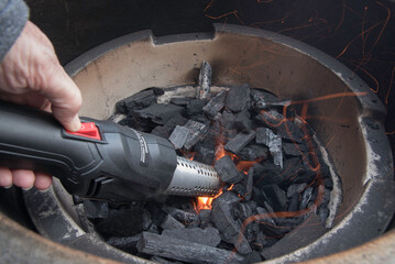 Using a torch devise to to light charcoal grill for cooking.