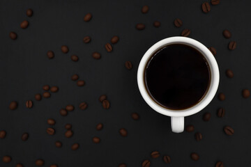 top view of white ceramic cup hot coffee roasted coffee beans on a dark background