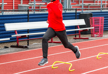 High school boy running over yellow mini hurdles on a track