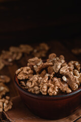 Walnuts close up in a brown bowl on a dark wooden background. Organic food concept.